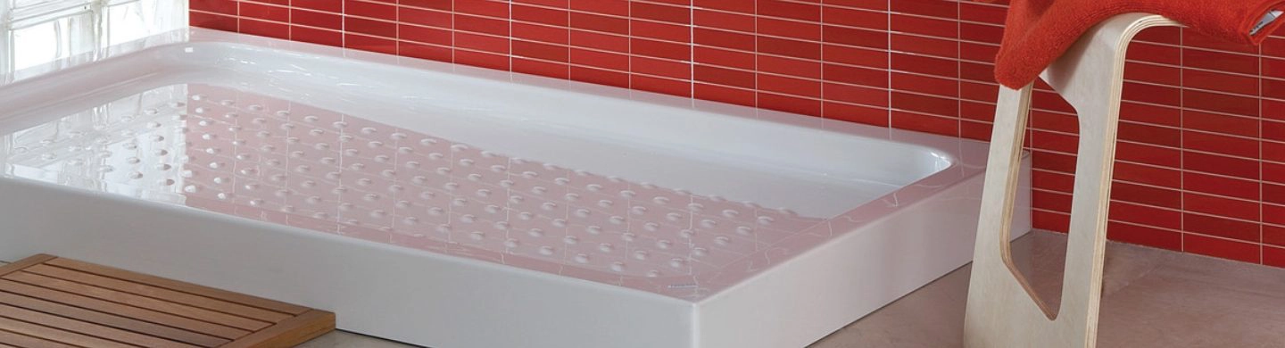 Detalle de plato de ducha blanco de cerámica con paredes del baño en color rojo