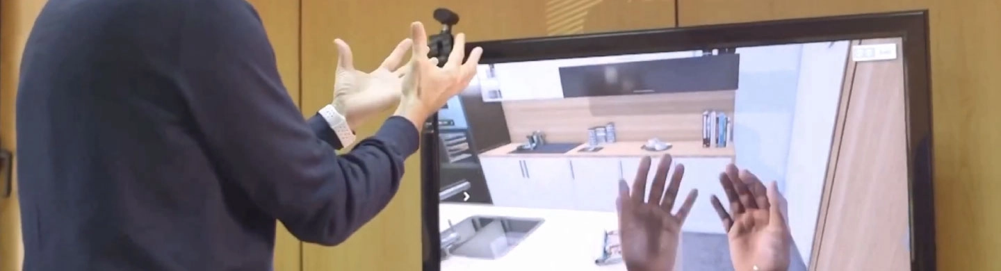 Hombre haciendo gesto con sus manos y viendo pantalla con cocina en realidad virtual
