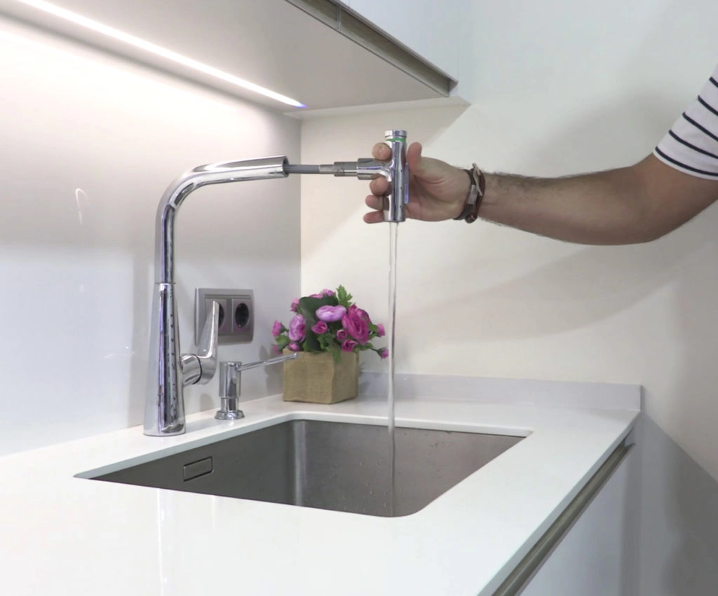 Detalle de grifo moderno abierto de lavabo integrado en encimera de laminado blanco brillo