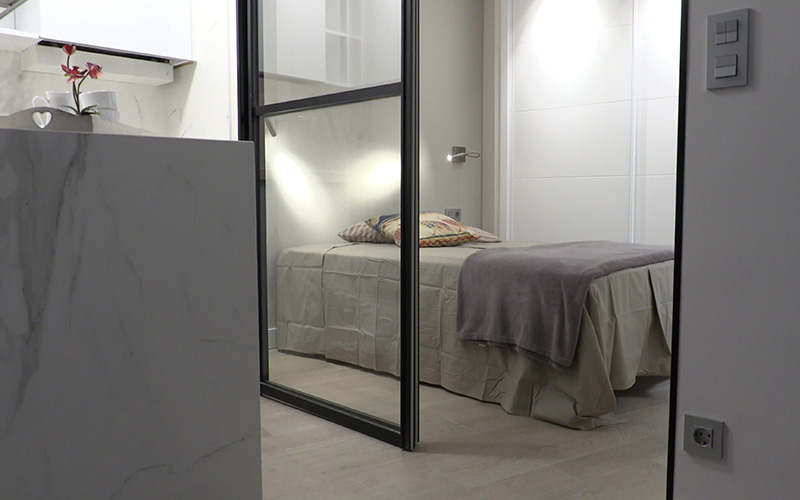 Detalle suelo, puerta corredera y cama en dormitorio - Proyecto Reforma de estudio pequeño en León