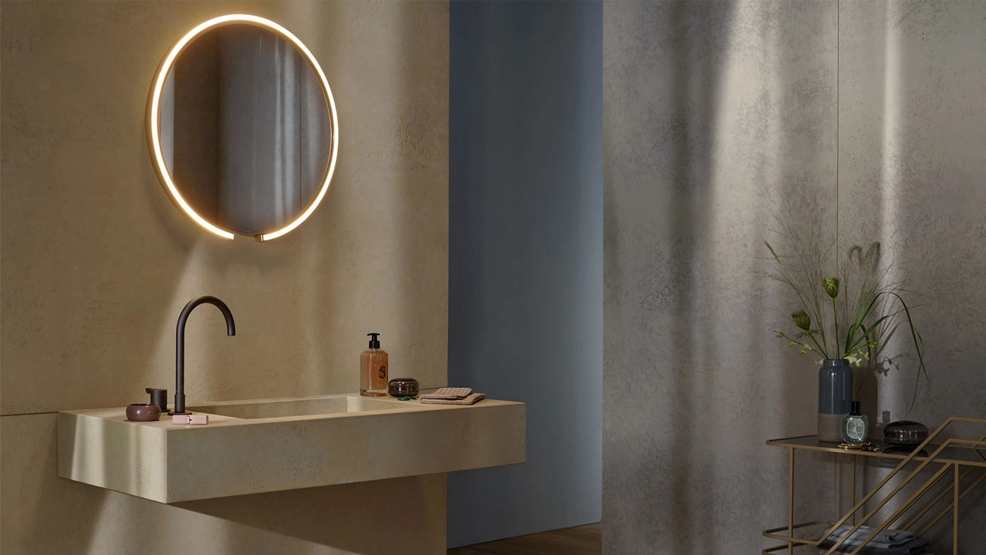 Vista frontal de lavabo de baño con iluminación sobre espejo circular