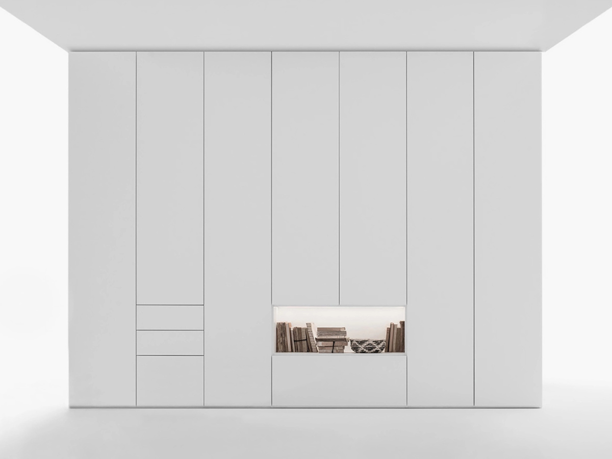 Vista frontal de armario Caccaro blanco a medida con apertura batiente con puertas cerradas y hueco para decoración o almacenaje.