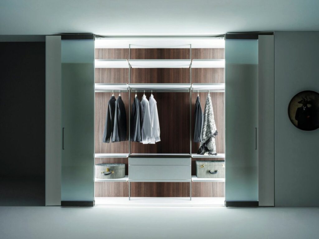 Vista frontal de armario Caccaro a medida con puertas de apertura total blancas abiertas con iluminación interior.