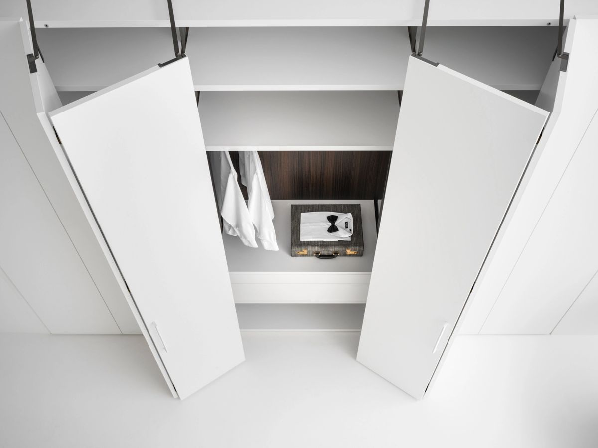 Vista desde arriba de armario Caccaro blanco a medida con apertura total y puertas entreabiertas.