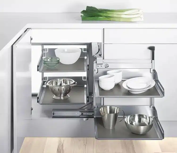 Mueble de cocina bajo situado en el rincón de color blanco con estantes extraíbles y utensilios en ella