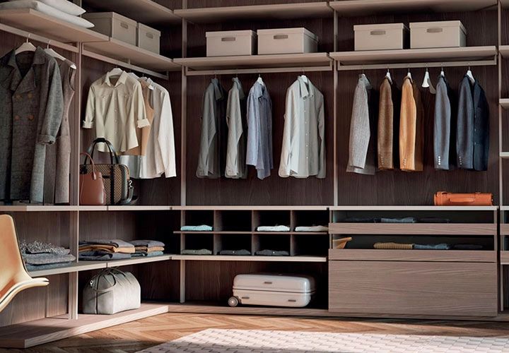 Vestidor abierto de Caccaro en acabado madera, en forma de ele, con ropa y accesorios organizados en él