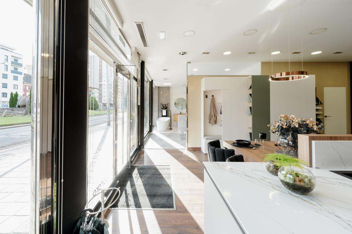 Interior tienda BUK Design león con exposición de cocina moderna seguida de un armario blanco y verde en el centro y un baño en tonos grises al fondo