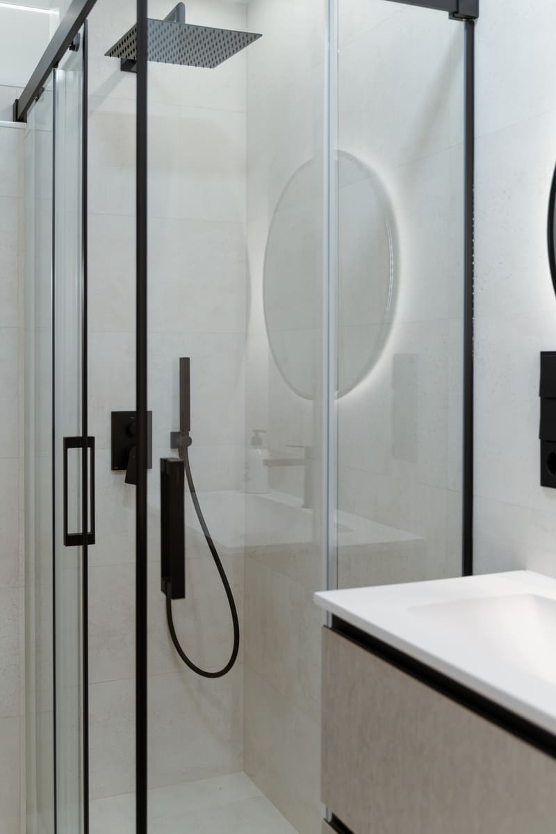 Detalle de la reforma del baño con mampara de perfilería negra e iluminación integrada