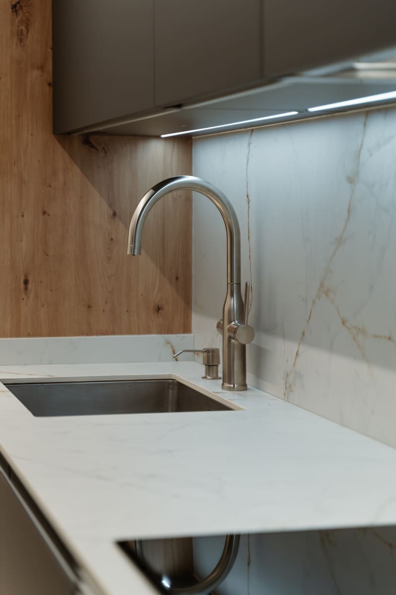 Detalle de reforma de cocina con lineas LED integradas y encimera de porcelánico Venatino Gold