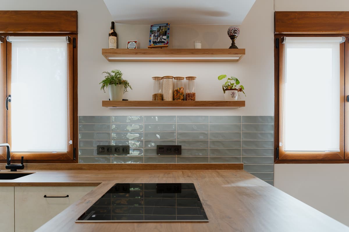 Cocina con muebles verdes, encimera de madera, estantes abiertos y alacena integrada.